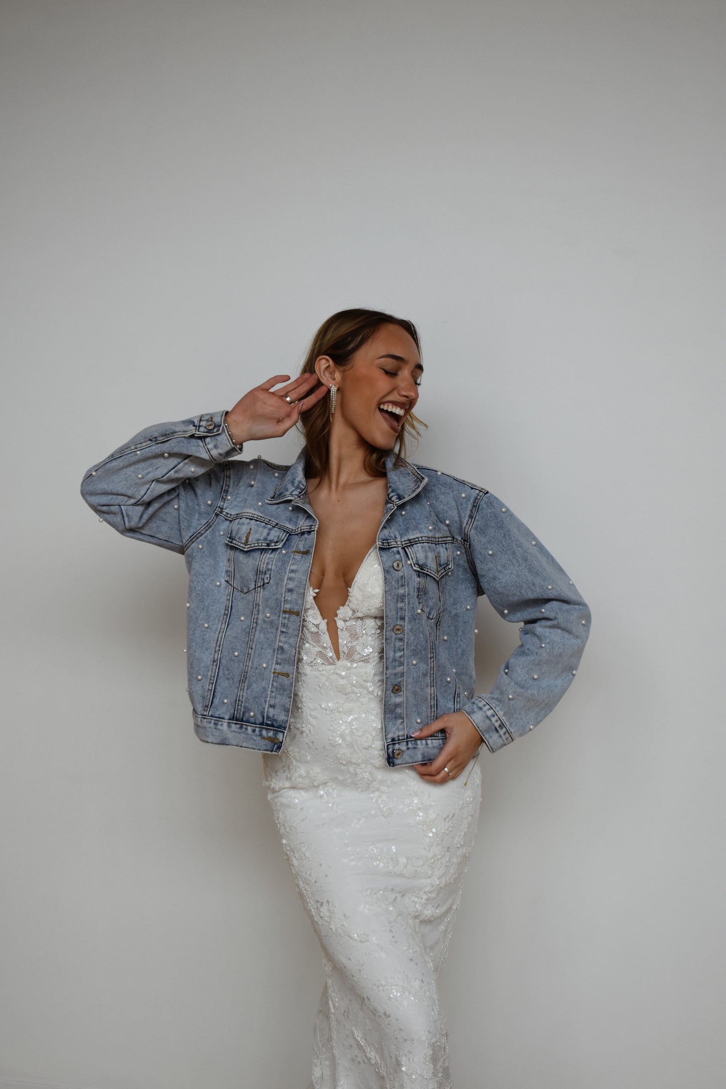 Bride wearing wedding dress and pearl jean jacket