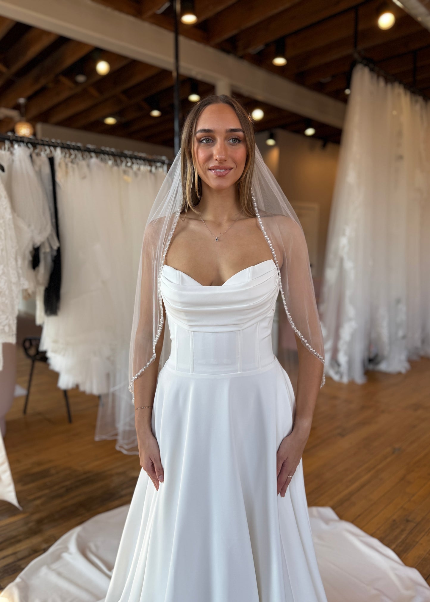 Woman wearing a white wedding dress with a veil in a bridal shop.