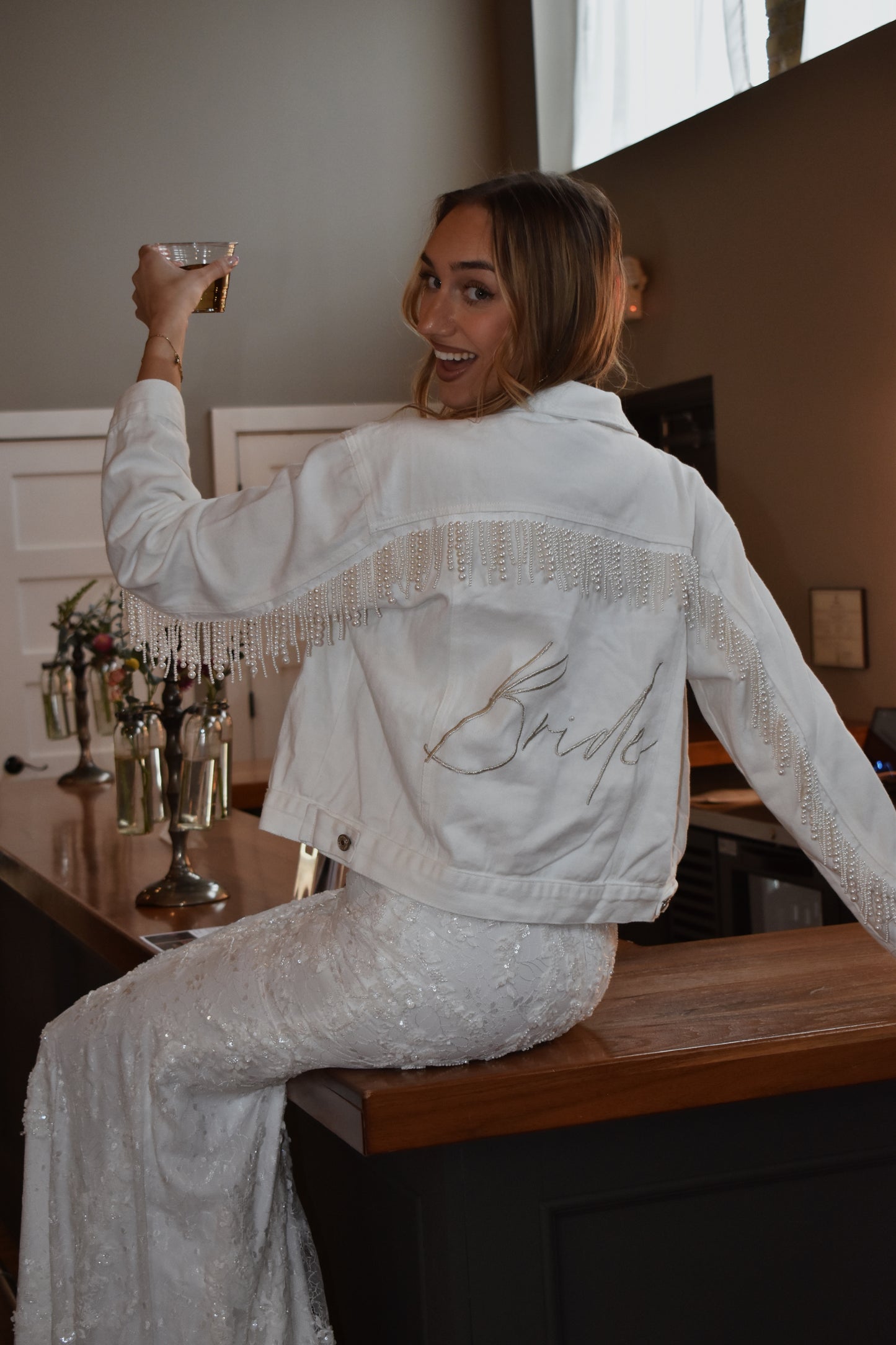 bride wearing white jean jacket with pearl fringe