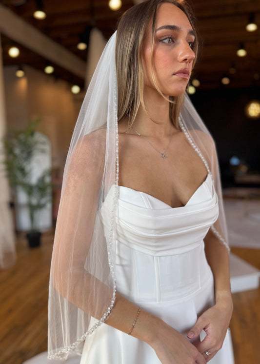 Woman wearing a white dress with a sheer veil indoors.