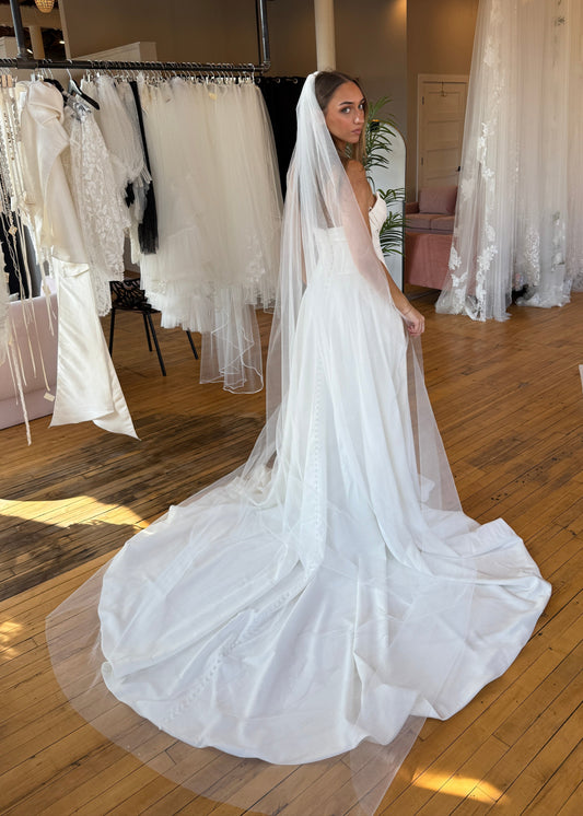 Woman holding a white wedding dress in a store