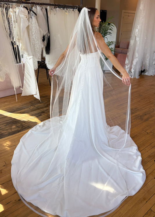 Woman wearing a ivory veil in a wedding dress in a store setting