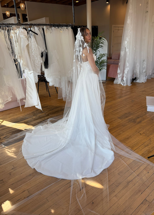 White wedding dress with a long train on a wooden floor